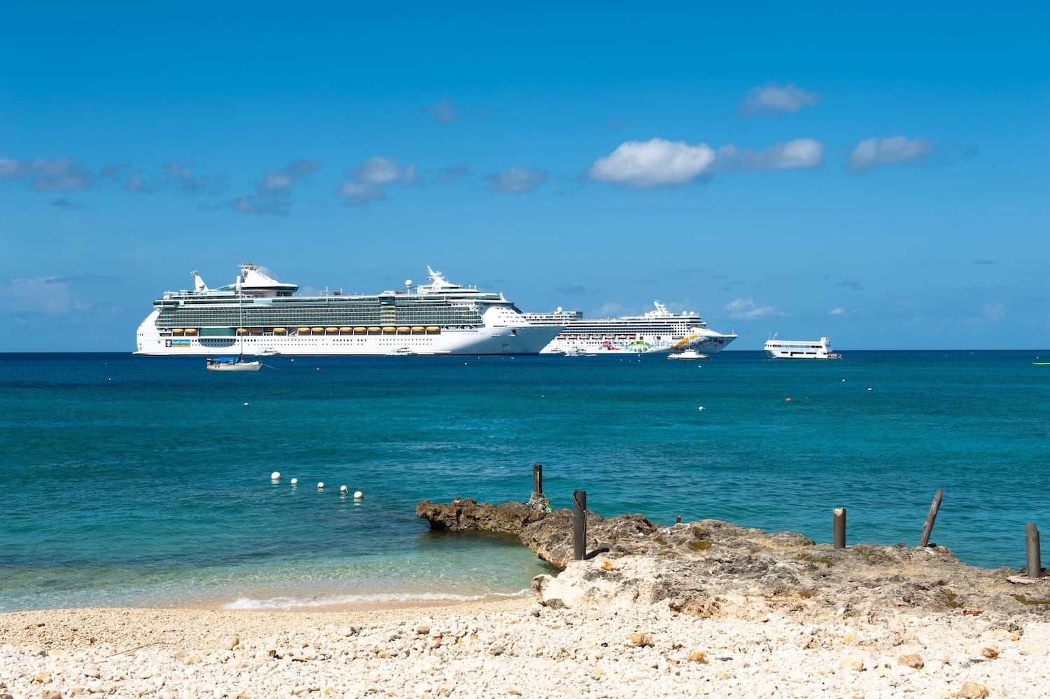 Multiple cruise ships anchored in turquoise waters off Grand Cayman coast during peak tourism season